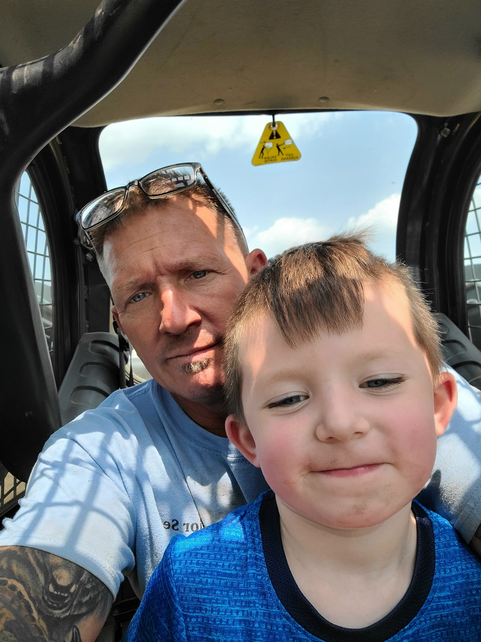 Chris Bolte and his grandson in the cab of a skid steer